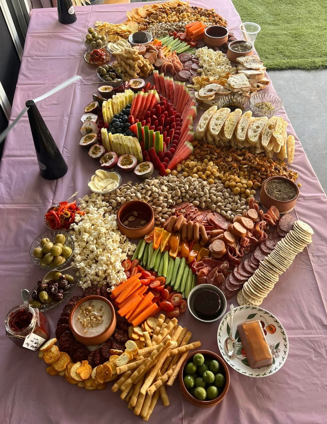 A long timber table at a Granite Belt vineyard wedding, set with grazing platters and tall candles, late afternoon sun catching the glassware.
